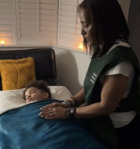Dahni giving Reiki to a child laying on a treatment bed during a Reiki for children Enfield Session 