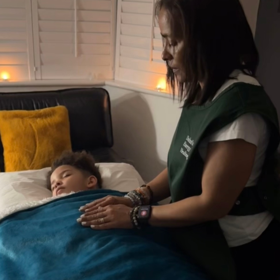 A child receiving Reiki Energy healing whilst laying down on a therapy couch/Bed