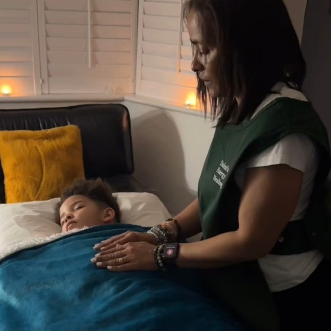 A child receiving Reiki Energy healing whilst laying down on a therapy couch/Bed